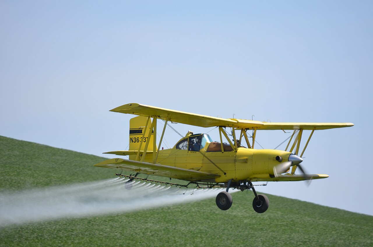 yellow crop duster spraying field