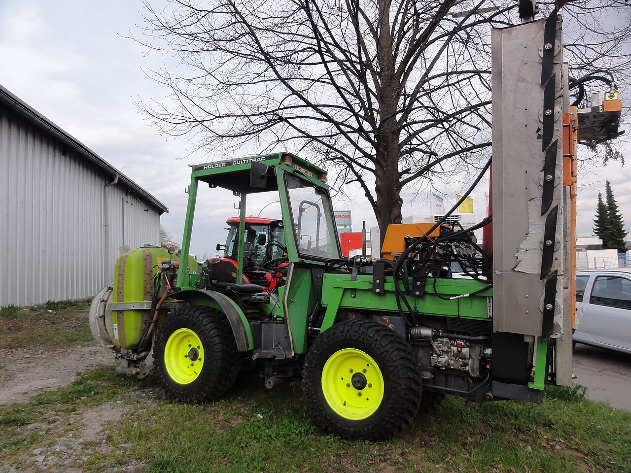 Traktor za nasade opremljen spremnikom za prskanje i priključkom za obradu redova